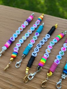 several different colored lanyards with name tags attached to them on a wooden table