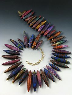 a necklace with many different colors and shapes on the front, along with a gold chain