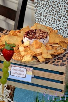 an assortment of crackers and fruit on a wooden box with leopard print napkins