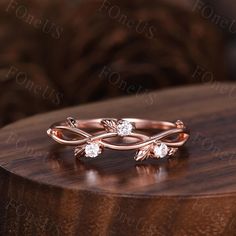 a rose gold ring with three diamonds on it sitting on a wooden table in front of a couch