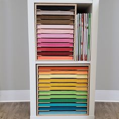 a white bookcase filled with lots of different colored papers on top of each other