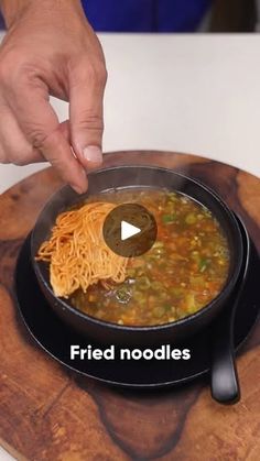 a person is cooking some food in a pan on a wooden board with the words fried noodles