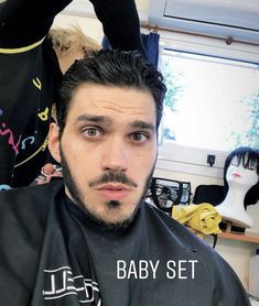 a young man getting his hair cut at the barbershop in front of him