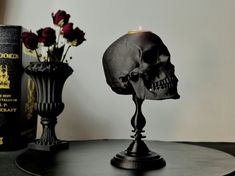 a skull head candle holder sitting on top of a black table next to a book