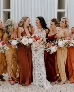 a group of women standing next to each other wearing dresses and holding bouquets in their hands