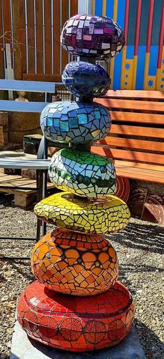 a stack of colorfully painted rocks sitting on top of a cement slab next to a wooden bench