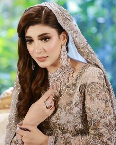 a woman in a bridal gown and veil posing for the camera with her hand on her hip