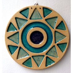 a blue and green ceramic object hanging on a wall