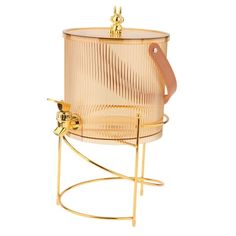 a gold colored ice bucket sitting on top of a metal stand with a leather handle