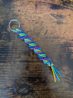 a keychain that has been made out of rainbow - colored string and is on top of a wooden table