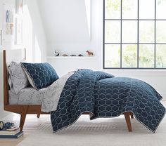 a bed with blue and white bedspread in a bedroom next to a window