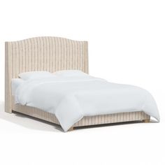 an upholstered bed with white sheets and pillows