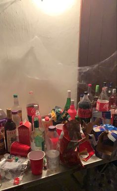 many bottles and glasses are sitting on the counter in front of a mirror with plastic wrap around them