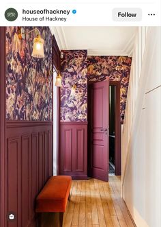 the hallway is decorated in purple and orange with floral wallpaper, along with an orange bench