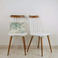 two white chairs sitting next to each other in front of a wall with the words wa 08