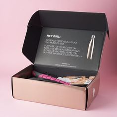 an open box with some items inside on a pink background