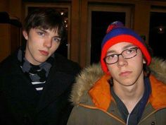 two young men standing next to each other in front of a door wearing beanies