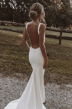 the back of a woman's wedding dress in front of a fenced area