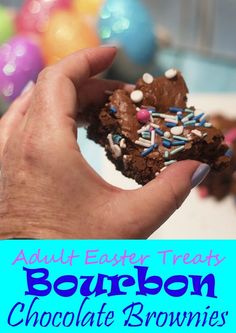 a hand holding a chocolate brownie with sprinkles and candy on it