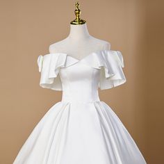 a white wedding dress on a mannequin with an off the shoulder neckline