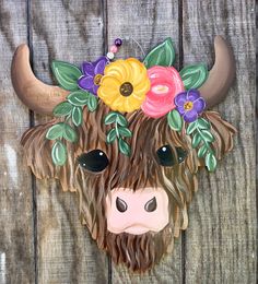 a cow with flowers on it's head is mounted to the side of a wooden fence