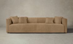 a tan couch with four pillows on it