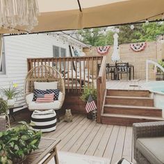 an outdoor deck with chairs, pillows and potted plants next to a hot tub