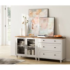 a white cabinet with drawers and pictures on the wall