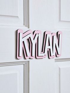 the word kylan is cut out of wood on a white door with pink trim