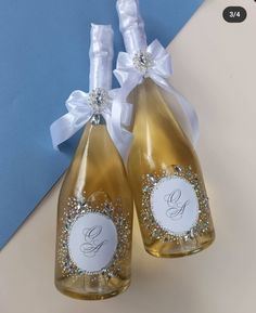 two champagne bottles with white bows and monogrammed labels