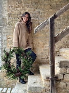 a woman is standing on the steps holding a wreath