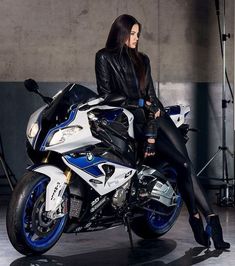 a beautiful woman sitting on top of a motorcycle in front of a camera set up