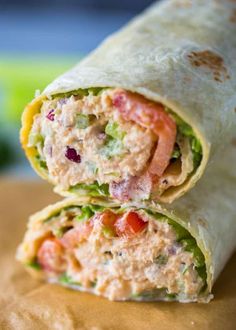 a wrap filled with meat and veggies sitting on top of a table