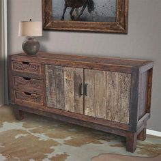 an old wooden sideboard with two drawers and a horse painting on the wall behind it