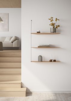 a living room filled with furniture next to a stair case and wall mounted bookshelf