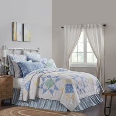 a white bed with blue and yellow quilted bedspread on top of it