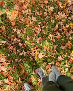 the person is laying down on the grass with their feet in the air and leaves all over them