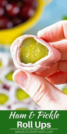 a hand holding a small cracker filled with hummus and pickle roll ups