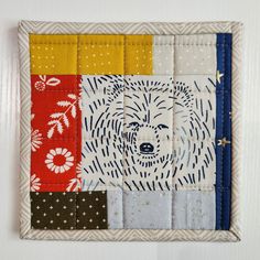 a patchwork wall hanging with a bear on it