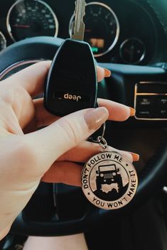 a person holding a keychain in their hand next to a car steering wheel