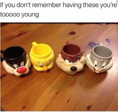 three coffee mugs sitting on top of a wooden table next to each other with faces painted on them