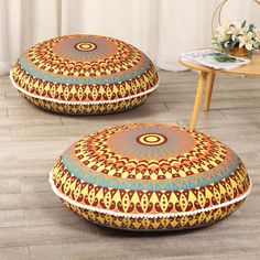 two round floor pillows sitting on top of a wooden floor next to a table and chair