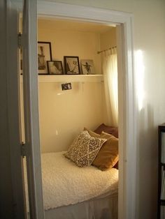 an open door leading to a small bedroom with a bed and pictures on the wall