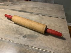 a wooden rolling pin sitting on top of a table next to a red handled knife