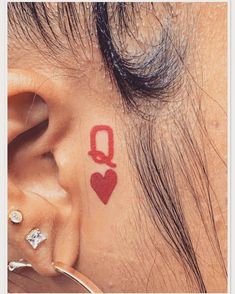 a girl with a heart tattoo on her ear and behind the ear is a red q