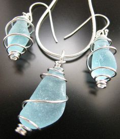 three pieces of sea glass sitting on top of a table next to silver wires and hooks