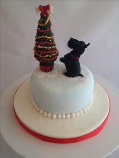 a white cake with a black dog and a christmas tree on top