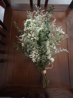 a bouquet of white flowers sitting on top of a wooden table next to a chair