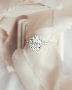 an engagement ring sitting on top of a pillow