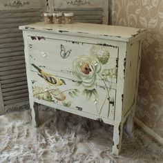 an old dresser painted with flowers and butterflies on the drawers is shown in this image